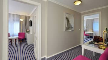 A hotel room with a striped carpet, a desk with a chair, a bed, and a large mirror.