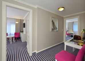 A hotel room with a striped carpet, a desk with a chair, a bed, and a large mirror. - Best Western Premier Parkhotel Kronsberg (Hannover)