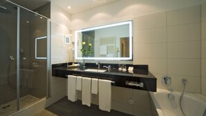 Een moderne badkamer met een douchecabine van glas, een grote spiegel en een bad.