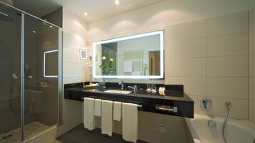 A modern bathroom with a glass-enclosed shower, a large mirror, and a bathtub.