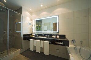 A modern bathroom with a glass-enclosed shower, a large mirror, and a bathtub.
