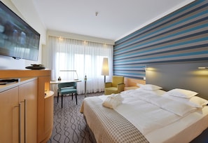 A hotel room with a bed, a desk, a chair, a television, and a striped wall. - Best Western Premier Parkhotel Kronsberg (Hannover)