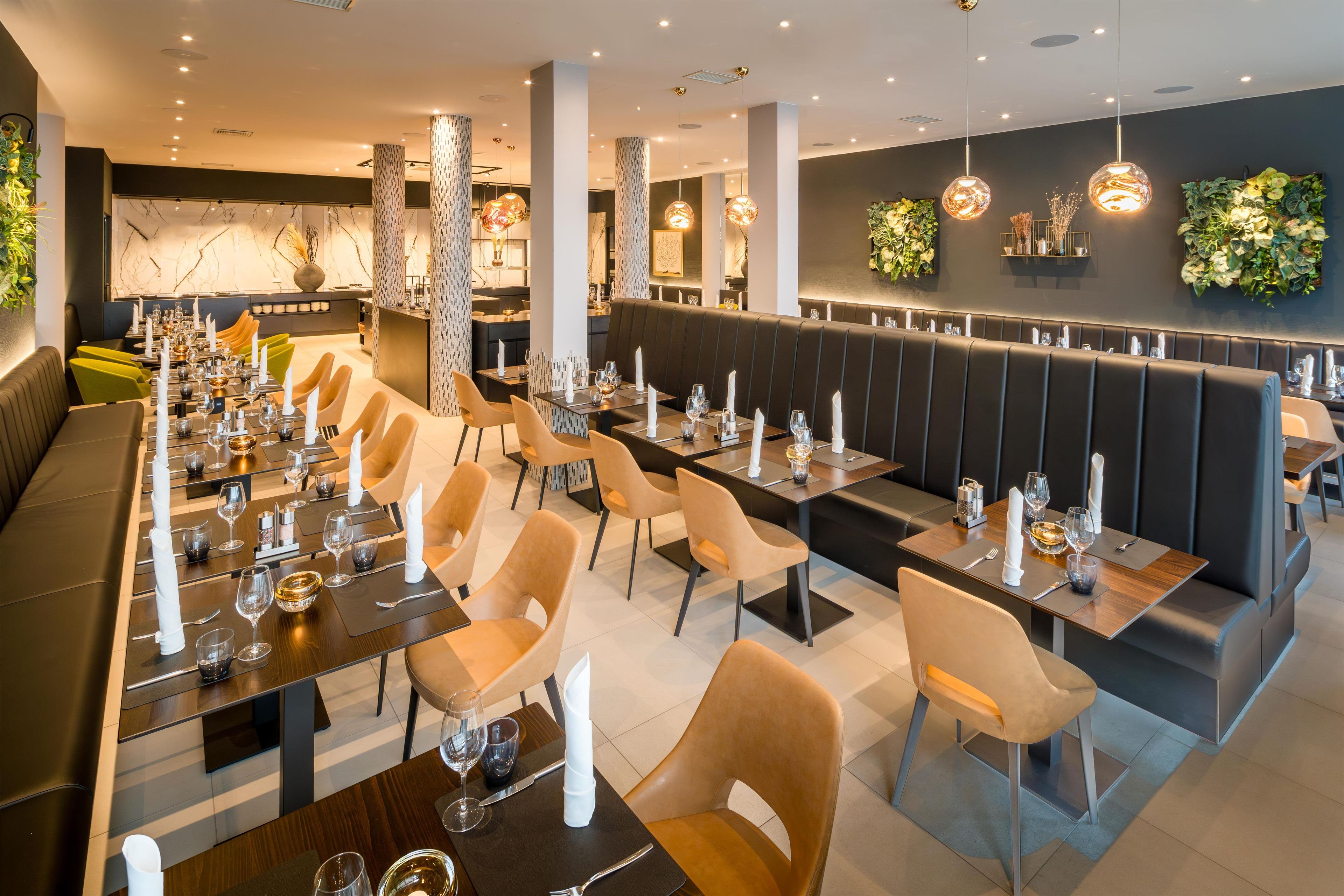 Interior modern d'un restaurant amb taules comunals llargues, seients individuals i zona de bar.