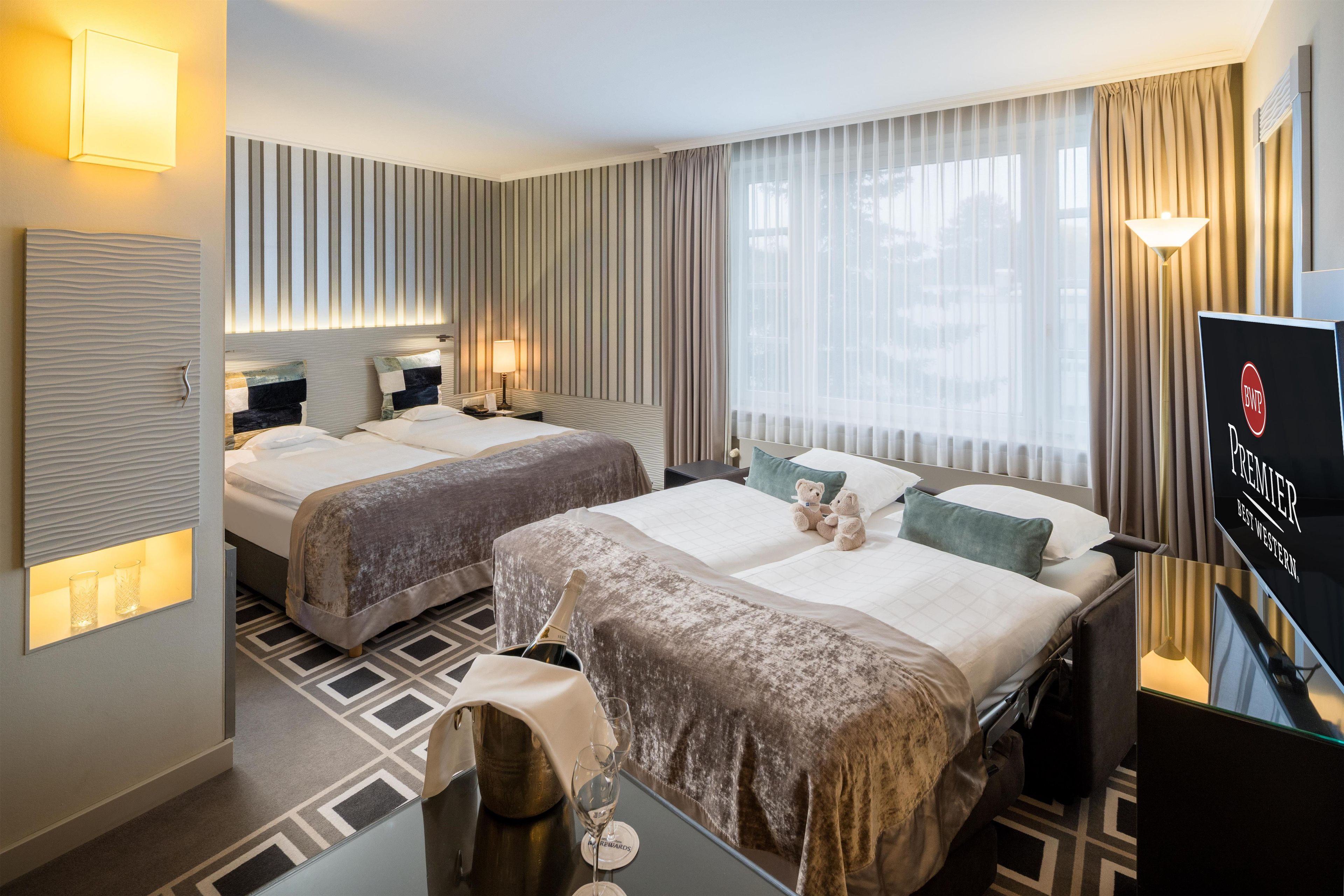 Ein Hotelzimmer mit zwei Betten, einer Minibar, einem Fernseher und Blick ins Freie.