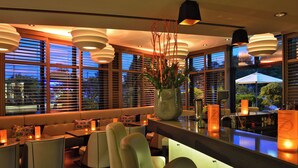 A modern bar area with seating, large windows, and decorative lighting.
