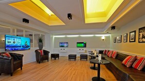 Een moderne woonkamer met een flatscreen televisie, comfortabele zitplaatsen en een houten vloer.