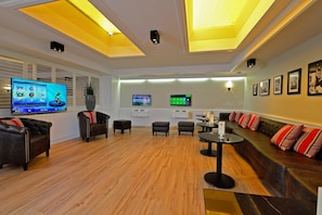 Een moderne woonkamer met een flatscreen televisie, comfortabele zitplaatsen en een houten vloer.