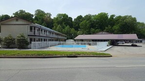 A motel with a swimming pool, a covered parking area, and a fenced parking lot. - Best Budget Inn (Tell City)