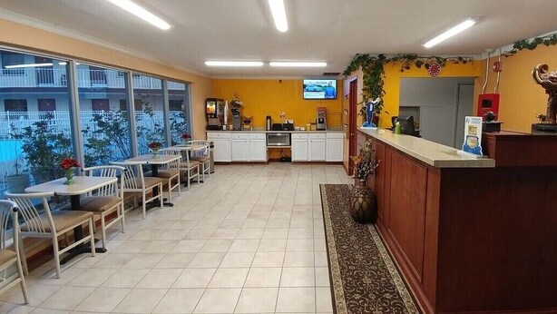 A hotel lobby with a reception desk, seating area, and large windows offering a view of the outside. - Best Budget Inn (Tell City)