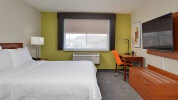 A hotel room with a bed, desk, chair, TV, and a window with a view.