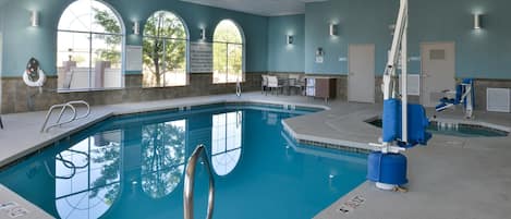 An indoor swimming pool with clear pool rules, emergency contact information, and a lifeguard chair.