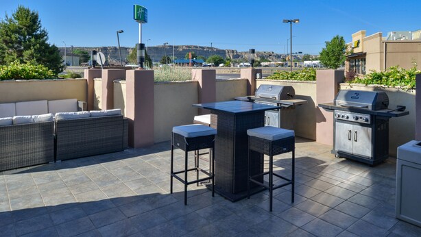 Eine Terrassengruppe im Freien mit Grill, Sitzgelegenheiten und Blick auf die Stadt.