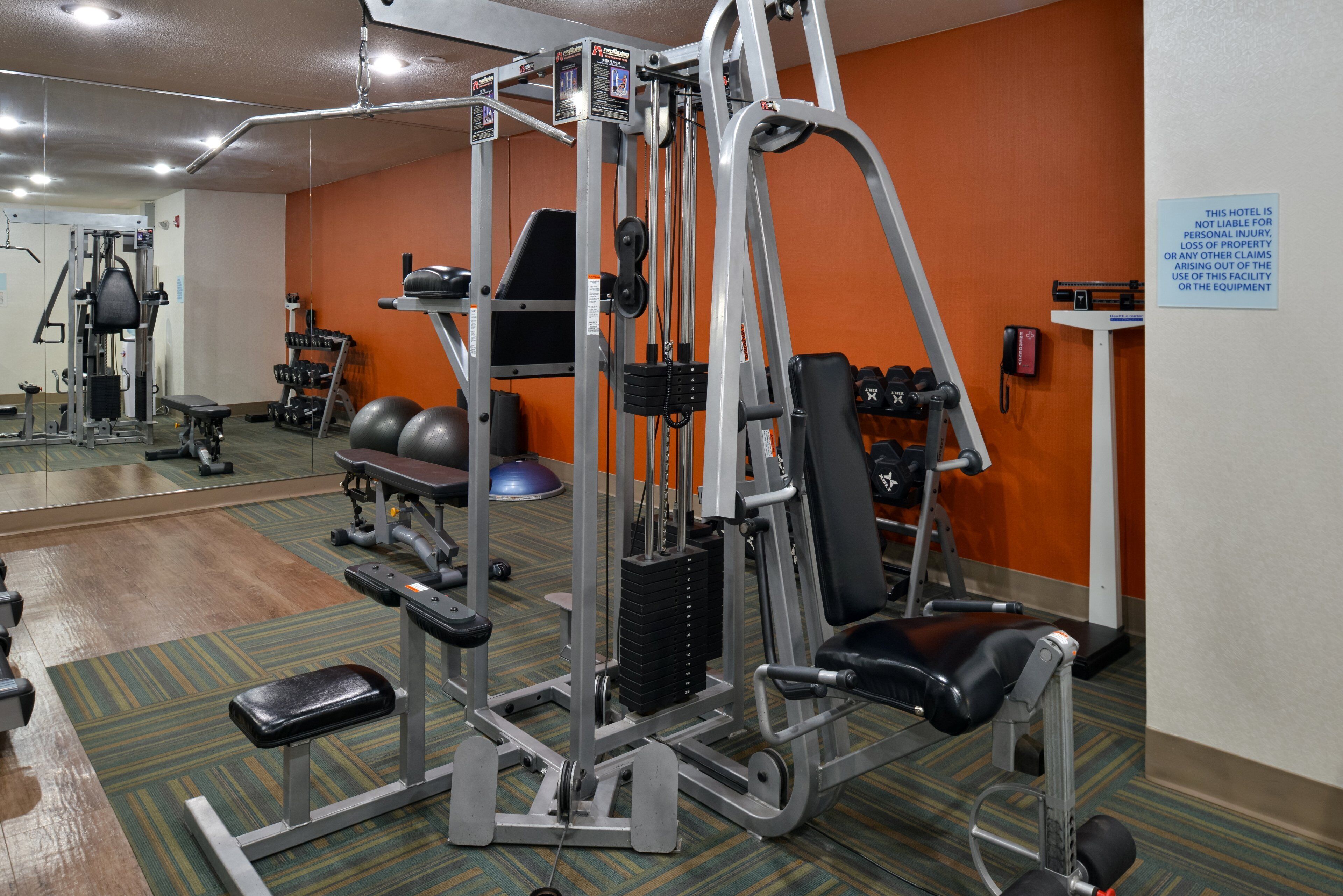 A hotel gym with various exercise equipment, including a squat rack, bench press, and dumbbells.