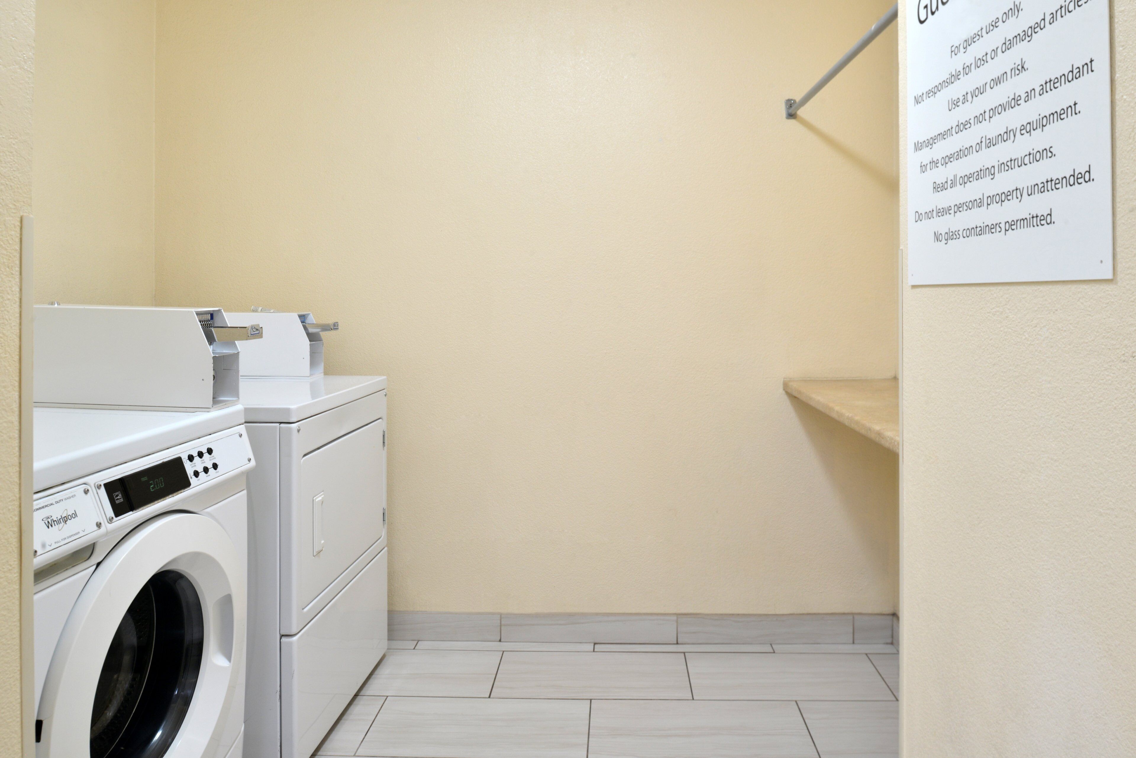 A laundry room with a Whirlpool washer and dryer, a wall-mounted towel rack, and a sign with laundry instructions.