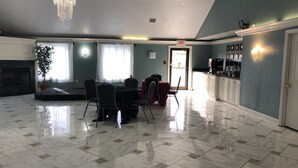 A spacious lobby with a marble floor, a chandelier, a fireplace, and a dining area with chairs and a table. - Araamda Inn Norcross (Norcross)