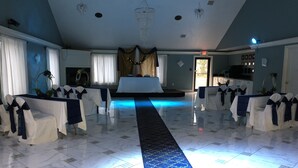 A spacious hall with a marble floor, rows of chairs with blue sashes, a central aisle, and a chandelier. - Araamda Inn Norcross (Norcross)