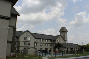 A multi-story building with a clock tower, a swimming pool, and a fenced courtyard.