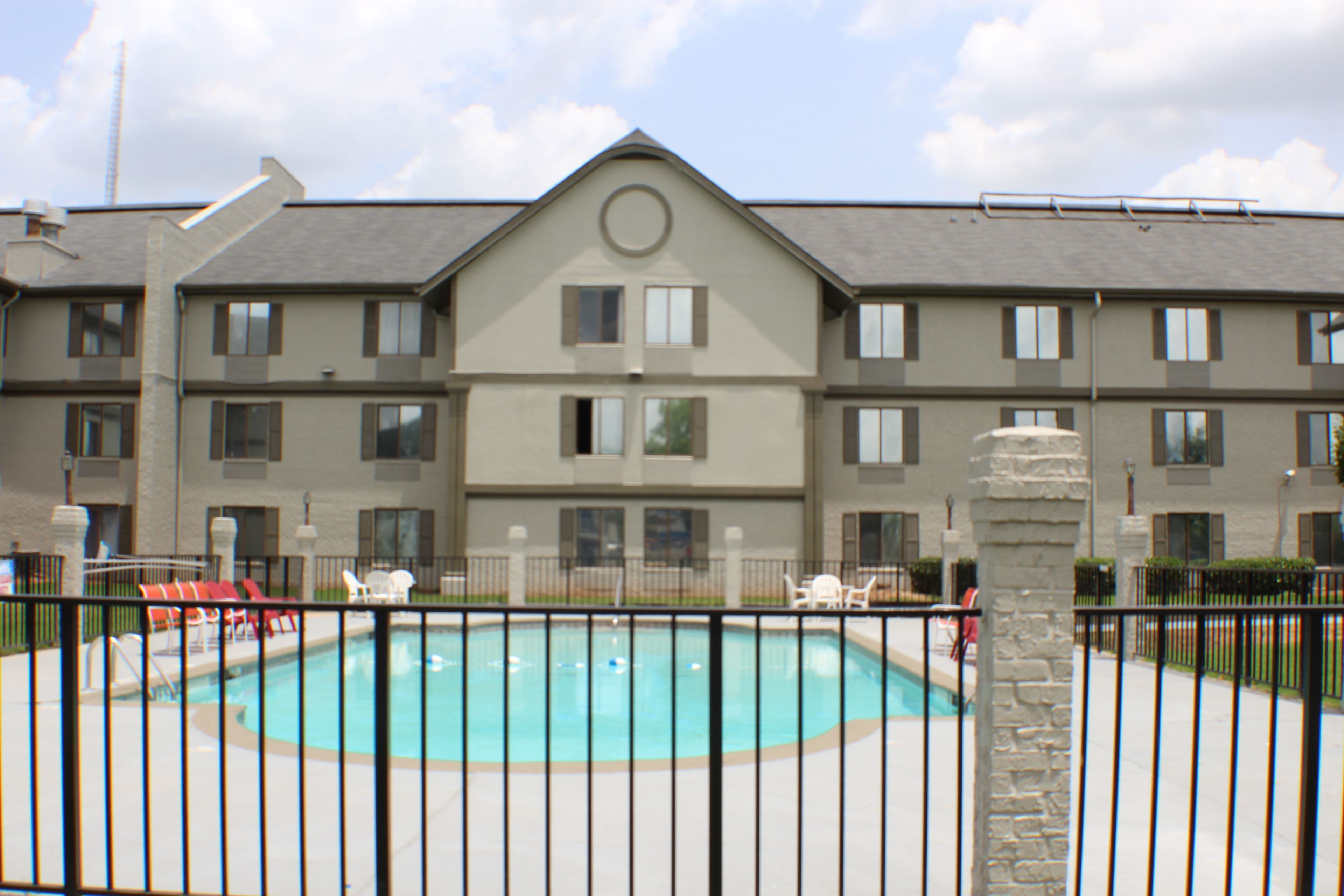 A multi-story hotel with a swimming pool surrounded by a black metal fence.