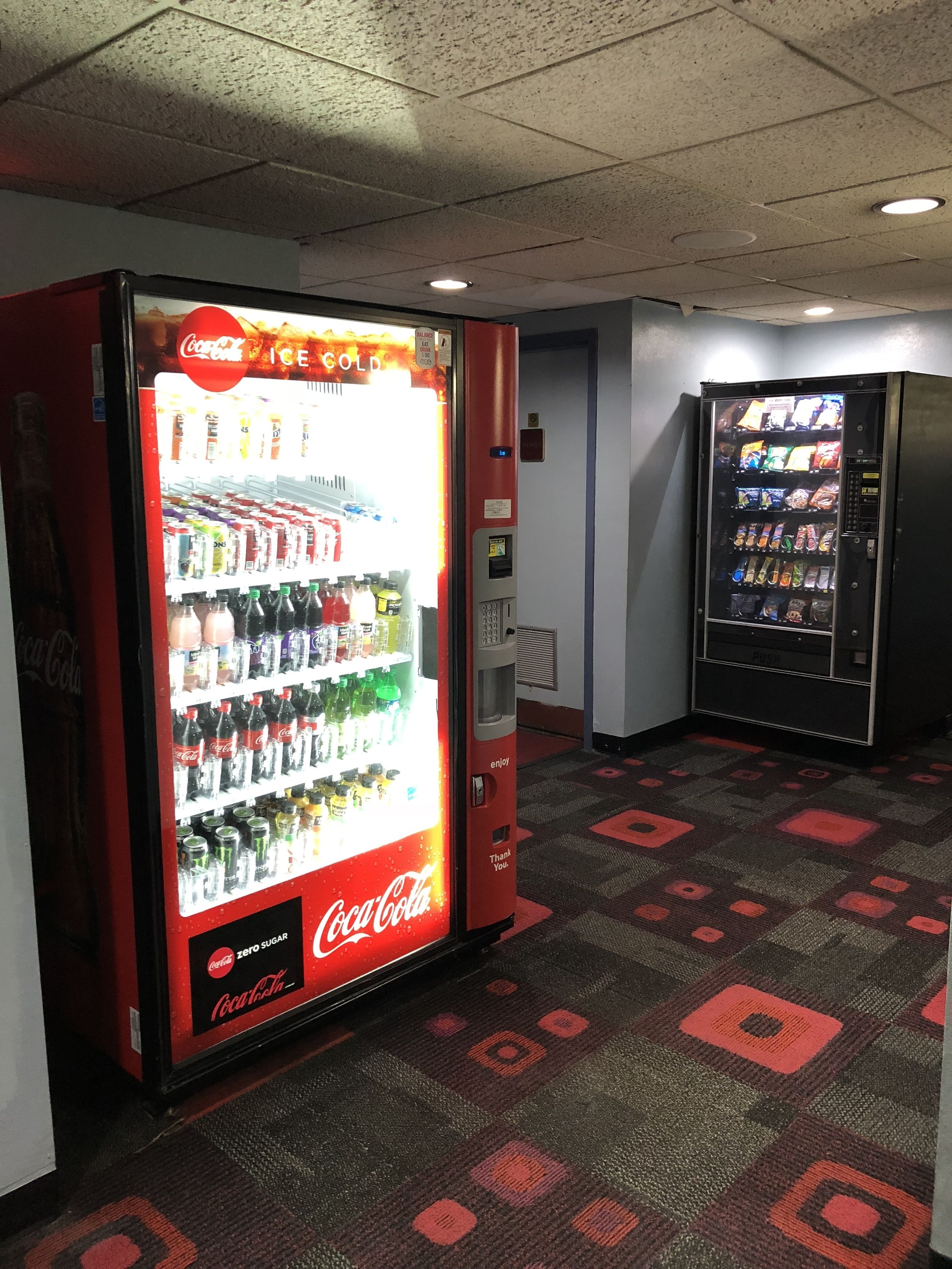 A vending machine area with Coca-Cola branded machines, including a selection of beverages and snacks.