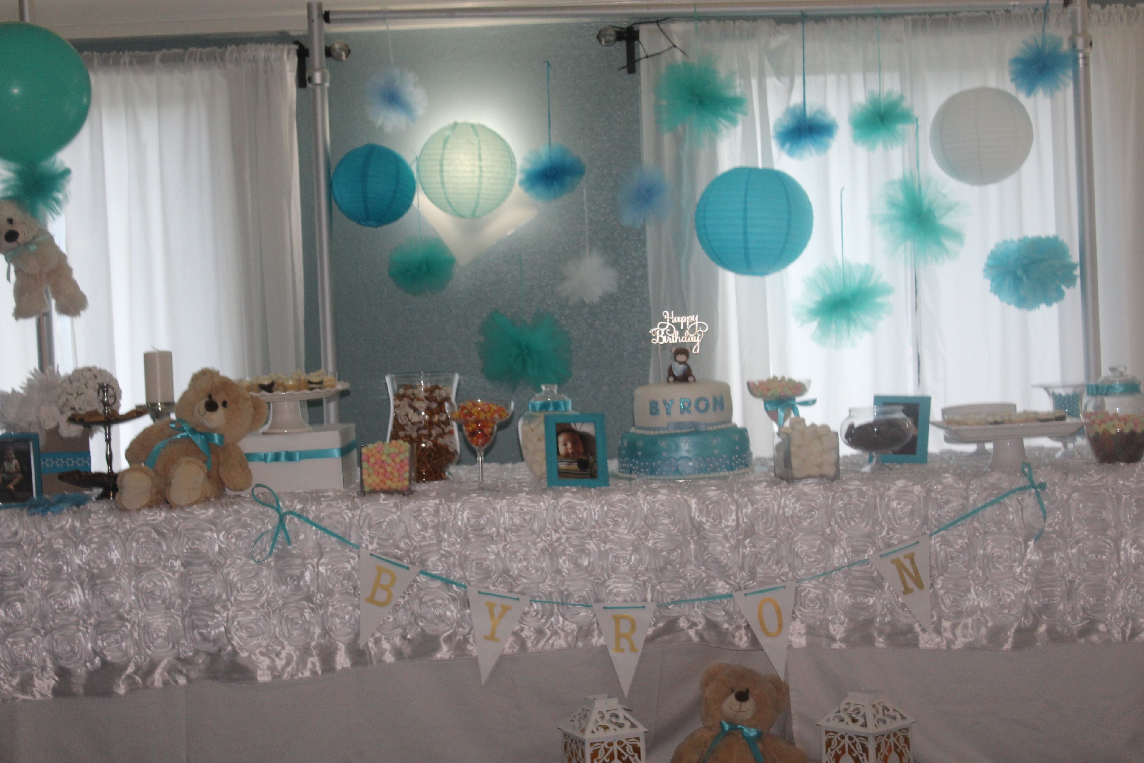Un espacio para eventos decorado con un cartel que dice "BYRON", destacando un peluche, globos y un pastel.