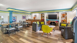A modern living area with a dining set, sofas, a TV, and a fireplace. - Econo Lodge Richmond-North Chesterfield (Richmond)