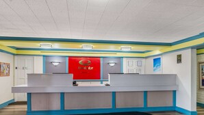 A reception desk with a red sign, blue accents, and a black mat in a hotel lobby. - Econo Lodge Richmond-North Chesterfield (Richmond)