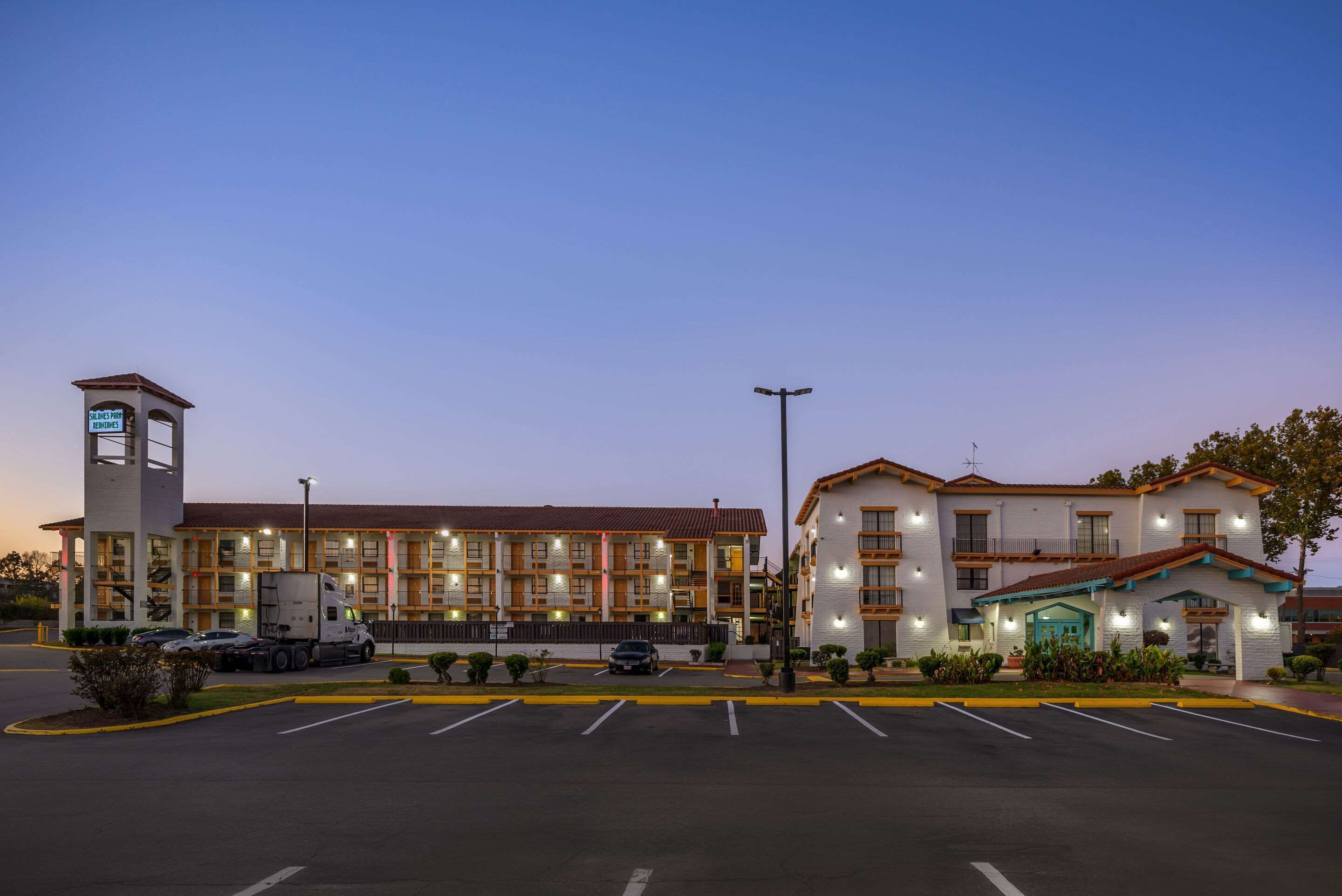 A hotel with a central tower, multiple floors, and a parking lot.