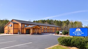 Een motel met twee verdiepingen, een groot parkeerterrein en een bord dat aangeeft dat het deel uitmaakt van de Americas Best Value Inn & Suites keten.