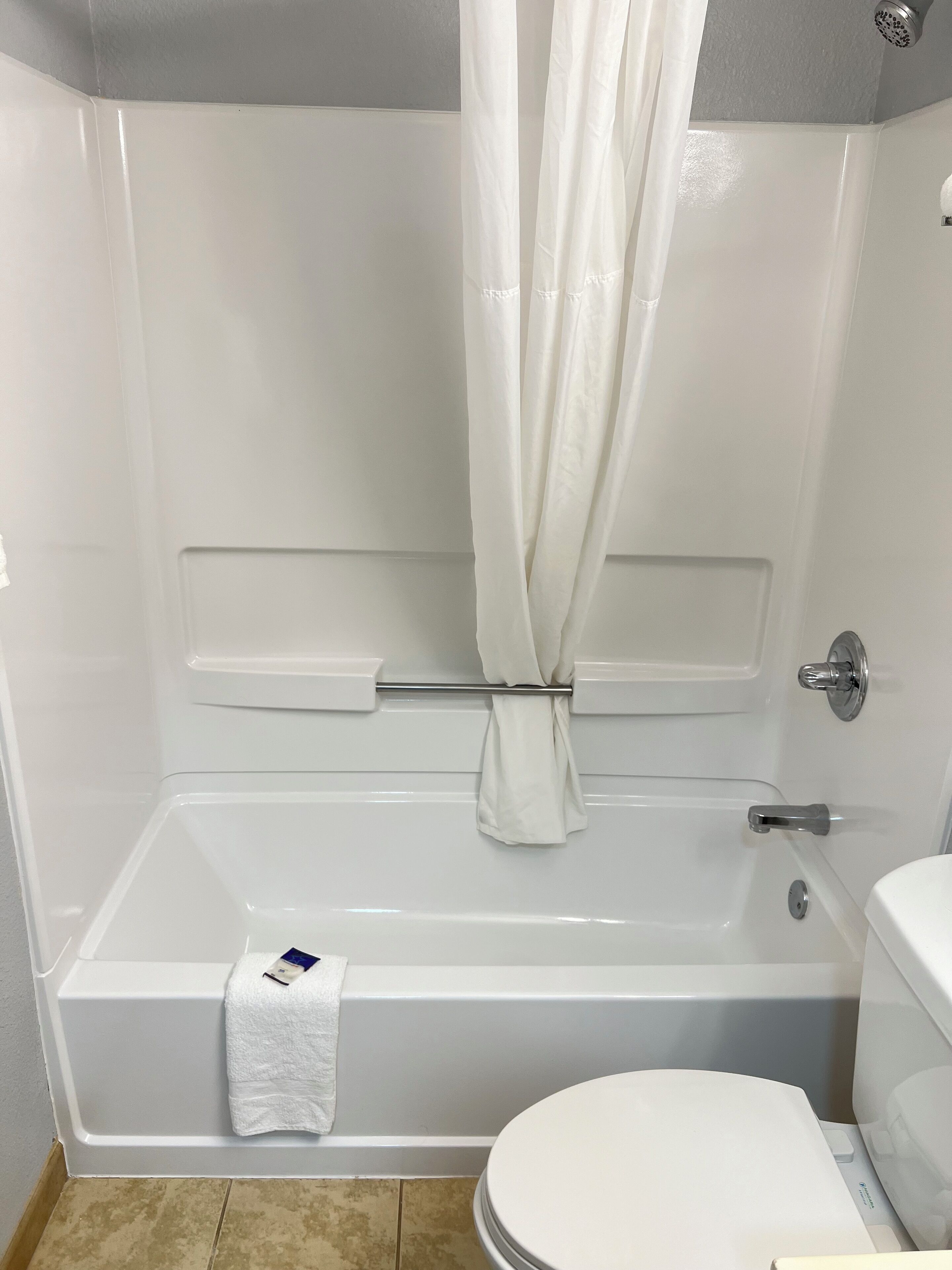 Et badeværelse med badekar, toilet og bruseforhæng.