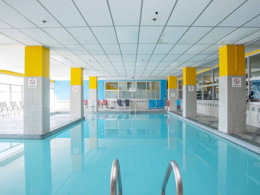An indoor swimming pool with clear water, yellow and white pillars, and a tiled ceiling.