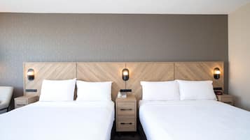 Quarto de hotel com duas camas, cabeceiras de madeira e luminárias laterais.