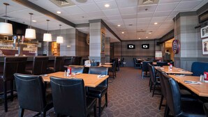 A restaurant with multiple tables and booths, a bar area, and a seating arrangement with a patterned carpet.