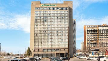A tall hotel building with a grid of windows and a sign reading "Sandman" at the top.