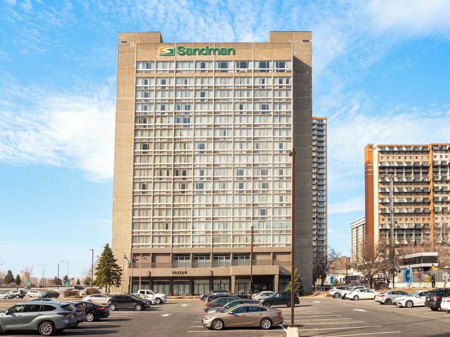 A tall hotel building with a grid of windows and a sign reading "Sandman" at the top.