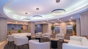 A modern lobby with a curved ceiling, seating area, reception desk, and elevators.