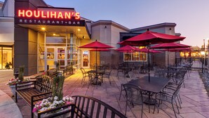 Houlihan's Restaurant & Bar with outdoor seating and red umbrellas. - Crowne Plaza Dulles Airport by IHG (Herndon)