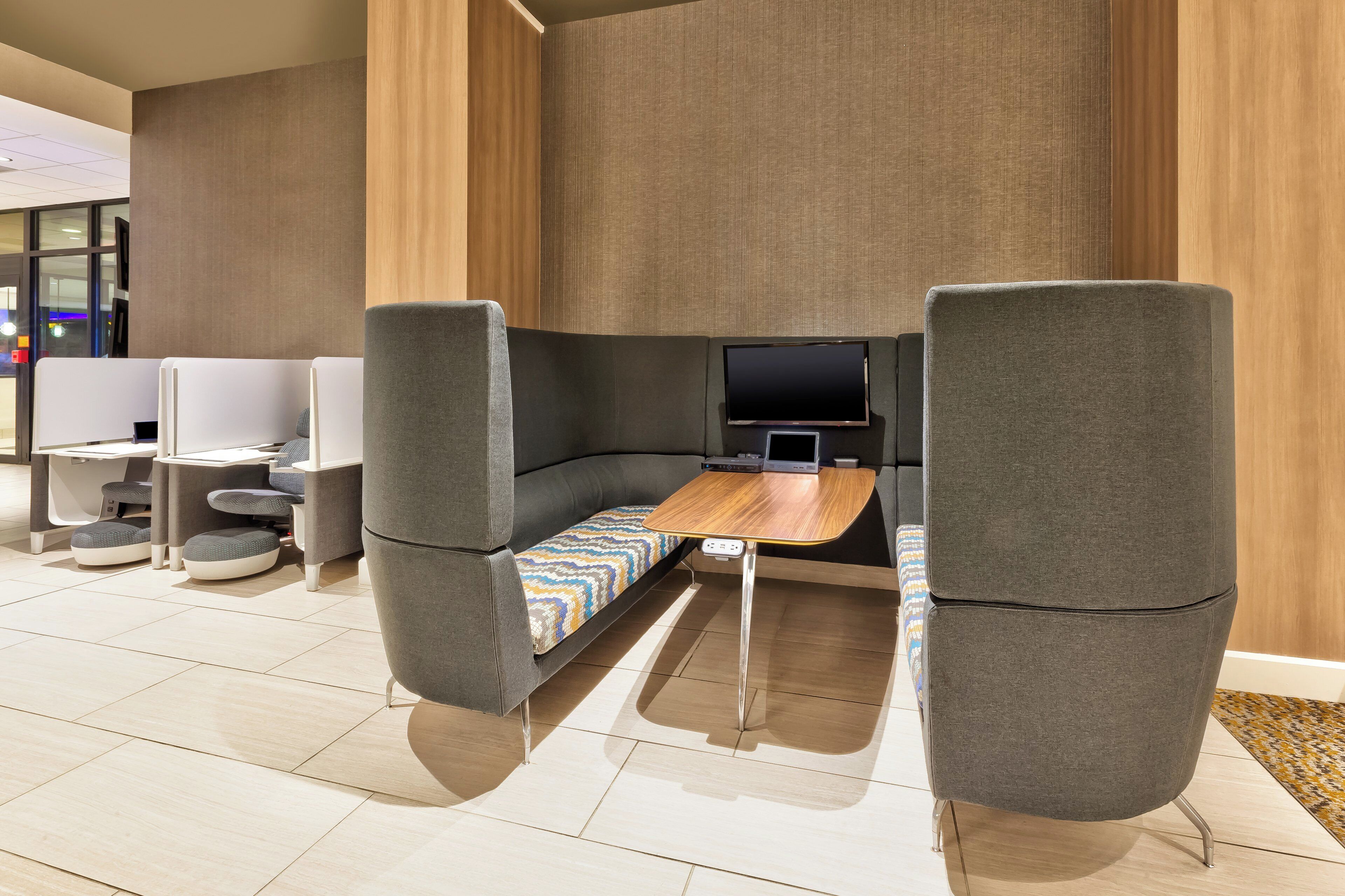 A modern, well-lit lounge area with a sofa, a small table, and a television.
