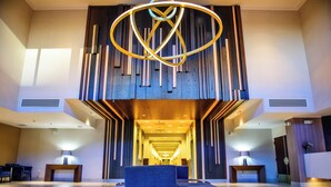 A modern lobby with a central light fixture, seating area, and a long corridor leading to the entrance. - Crowne Plaza Dulles Airport by IHG (Herndon)