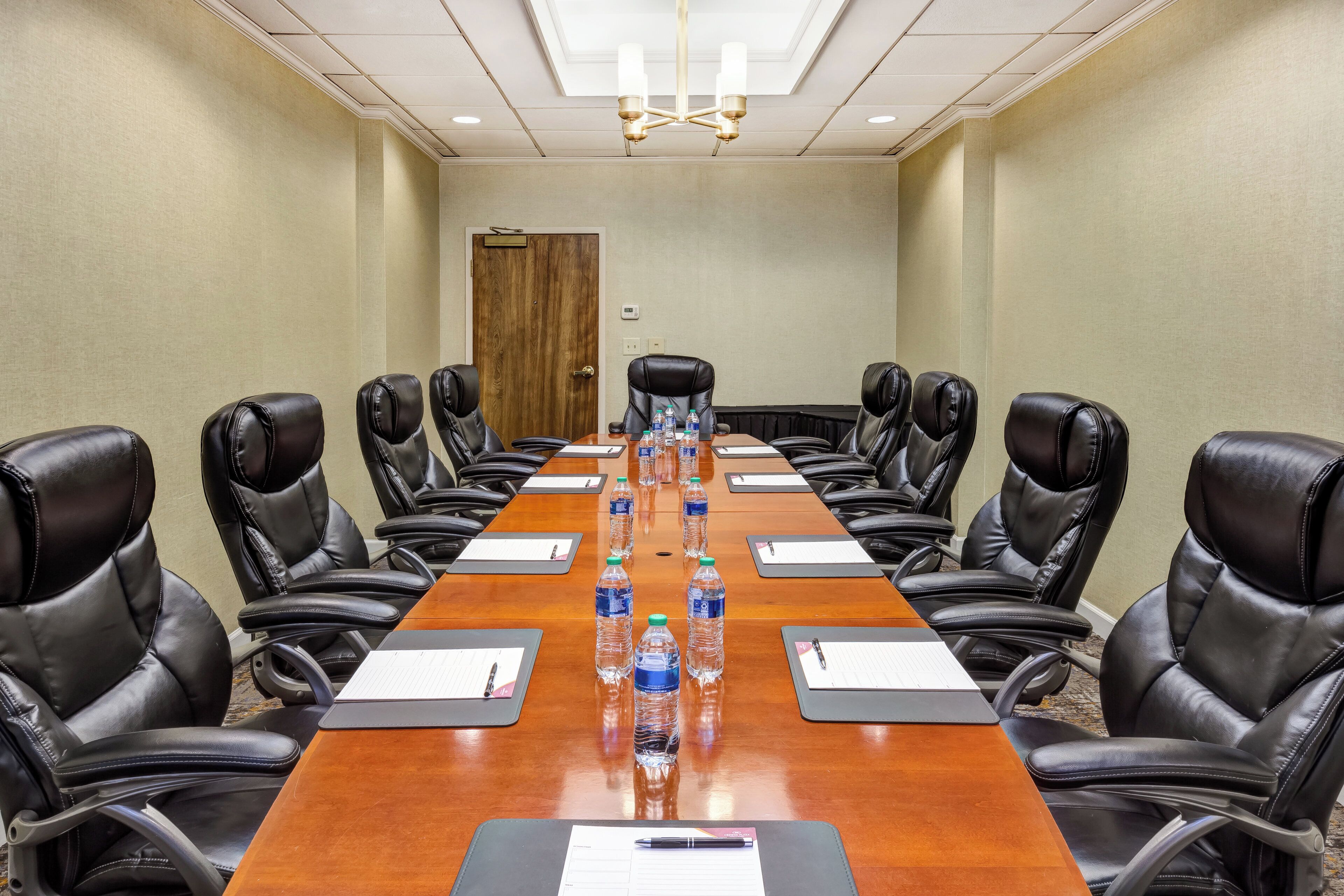A conference room with a long table, black leather chairs, water bottles, and nameplates.