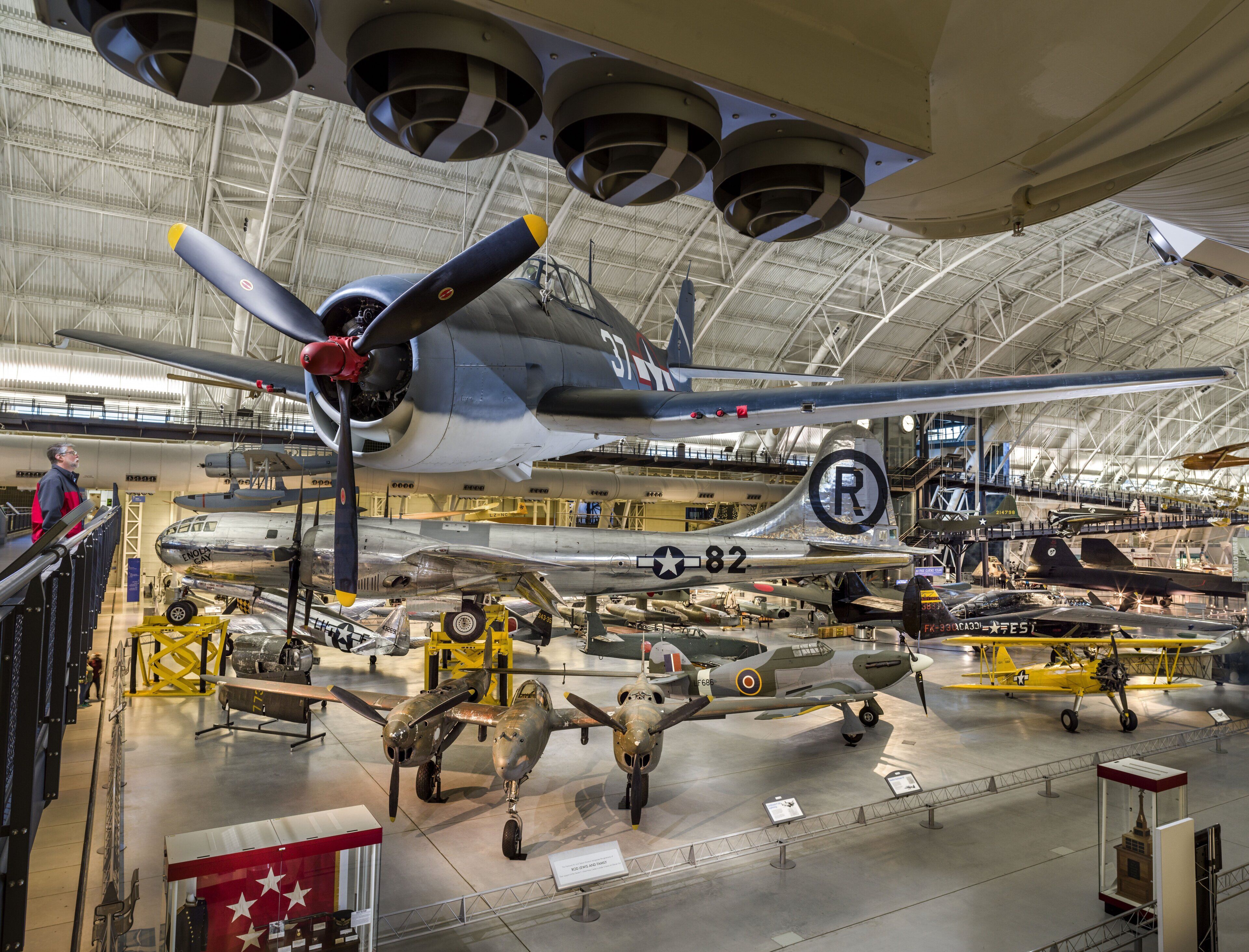 A large aircraft hangar with multiple vintage military planes on display.