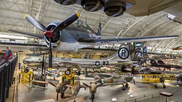 A large aircraft hangar with multiple vintage military planes on display.