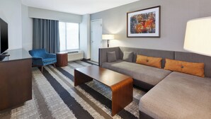 Een moderne hotelkamer met een bank, fauteuil en een flatscreen televisie.