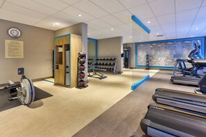 Une salle de sport équipée de tapis de course, d’haltères et d’un appareil d’aviron.