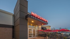 A restaurant with a prominent sign, outdoor seating with red umbrellas, and a brick facade. - Crowne Plaza Dulles Airport by IHG (Herndon)