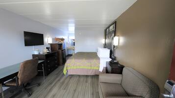 Una habitación de hotel con una cama, un escritorio, una silla, un televisor y un aparador.
