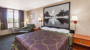 Habitación de hotel con una cama grande, dos lámparas de noche, una silla, un escritorio con un teléfono y un cuadro grande del edificio del Capitolio.