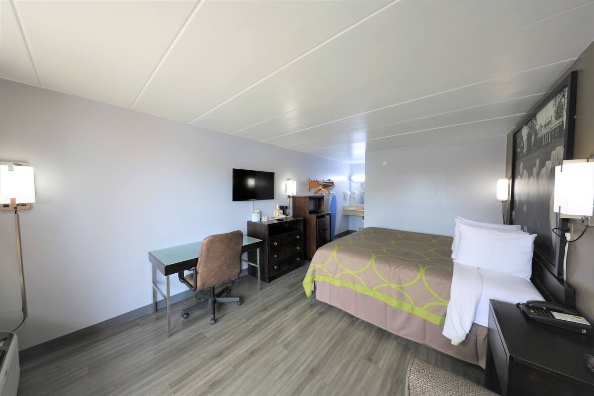 Ein Hotelzimmer mit Bett, Schreibtisch, Stuhl, Fernseher und Kommode.