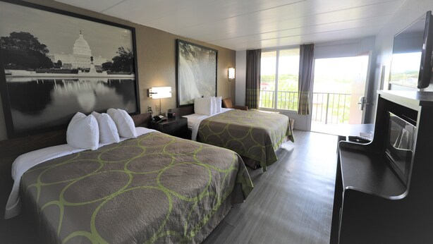 Habitación de hotel con dos camas, televisión, escritorio y ventana grande con vista al edificio del Capitolio.