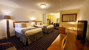 Habitación de hotel con dos camas, un banco de madera, un escritorio, un espejo y una alfombra estampada.