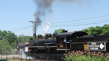 Eine Dampflokomotive mit der Nummer 40 stößt Dampf aus und steht an einem Bahnhof, an dem ein Schild 'Essex Steam Train Parking' zu sehen ist.